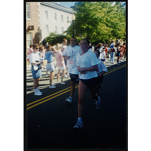 A teenage girl, a boy, and a man run past spectators during the Battle of Bunker Hill Road Race