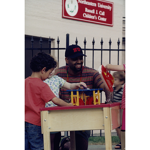 Children and a Northeastern student playing in front of Northeastern's Russell J. Call Children's Center