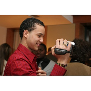 Odalis David Polanco holds a video camera in his hand at a Torch Scholars event