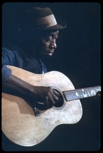 Mississippi John Hurt: studio portrait, seated, playing guitar