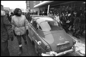 Protesters in the streets of Montpelier, walking past a Saab automobile during a demonstration against the invasion of Laos