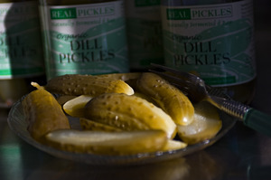 Sliced pickles from Real Pickles, in front of an array of jars