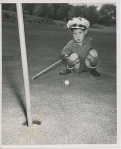 Billy Bruckner crouching with golf club and ball