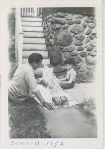 Paul Kahn and his father David painting a fence