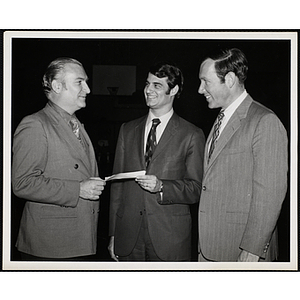 Donald C. Murray [?], at left, holding a check with an unidentified man as another man looks on