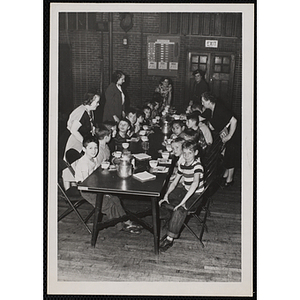 Women attend to a group of boys at a table during a Mothers' Club event