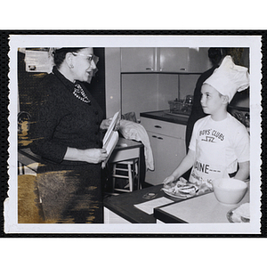 A member of the Tom Pappas Chefs' Club and an unidentified woman exchange glances in a kitchen