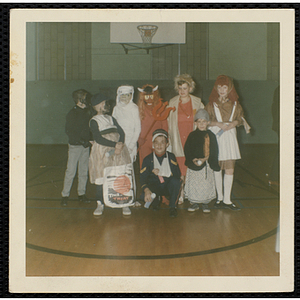 Children in Halloween costumes pose for a group shot in a gymnasium