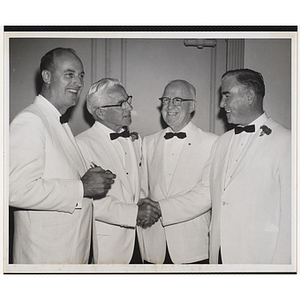 Four committee members standing together while two of them shake hands at a Boys' Club event