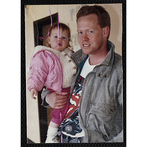 A man holding a baby girl and posing at a joint Charlestown Boys & Girls Club and Charlestown Against Drugs (CHAD) event