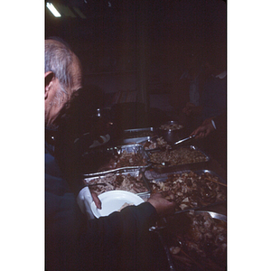 Association member serves himself food from a buffet spread at an International Women's Day dinner