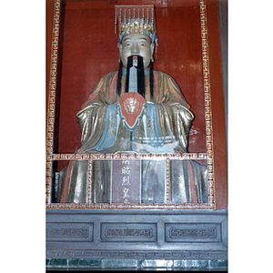 Statue of a man wearing a beaded headdress and golden robe