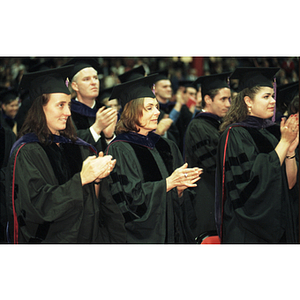 Three School of Law graduates clapping at the commencement ceremony for the Class of 1997