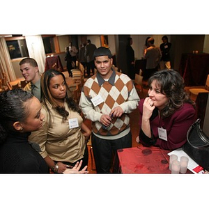 A woman converses with three Torch Scholars at an event