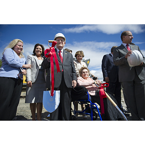 George J. Kostas stands surrounded by his family, holding a ceremonial shovel at the groundbreaking ceremony for the George J. Kostas Research Institute for Homeland Security