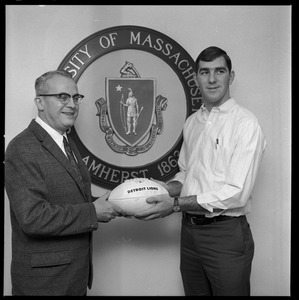 Greg Landry (UMass Amherst football quarterback) and University of Massachusetts President John W. Lederle holding a ceremonial football