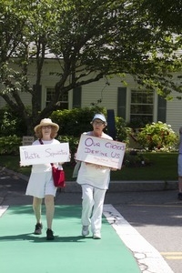 Two women pro-immigration protesters in a cross-walk over Main Street carrying signs reading 'Hate separates' and 'Our choices define us' : taken at the 'Families Belong Together' protest against the Trump administration's immigration policies