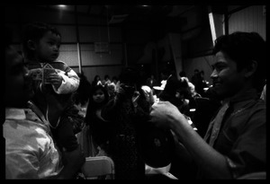 Cambodian New Year's celebration: man with baby holding cash, and drummer