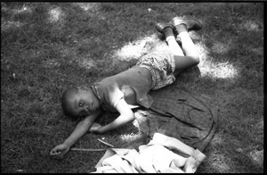 Young boy sprawling on the grass in a park
