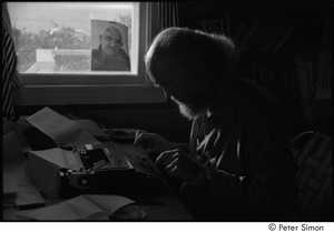 Ram Dass at typewriter: Ram Dass typing, with a portrait of Neem Karoli Baba in the background