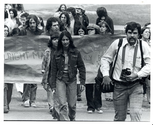 Board of Trustees fee increase demonstration: photographer and protestors holding banner marching from the Student Union to the Whitmore Administration Building