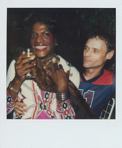 A Photograph of Marsha P. Johnson Holding a Glass and a Fur Scarf While Sitting on Someone's Lap