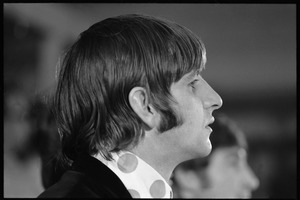 Ringo Starr seated at a table during a Beatles press conference: close-up in profile