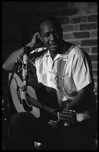 Josh White performing on guitar in a coffeehouse