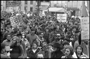 Anti-war protesters marching in the streets at the Counter-inaugural demonstrations, 1969, with banners and signs: 'Promises promises,' 'End racism,' and 'While government talk, children die'