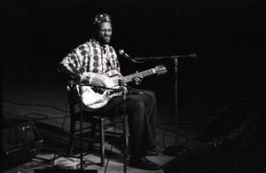 Taj Mahal in concert at Northfield, Mass.: Taj Mahal seated, playing steel guitar