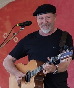 Richard Thompson: half-length portrait with guitar, smiling, on stage at the Clearwater Festival