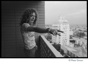 Robert Plant (Led Zeppelin) looks at Sunset Strip from a balcony at the Riot House, pointing at a billboard advertising the Physical Graffiti album