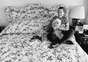 Marjorie Sundlun seated on a bed with her dog, Governor, at her Providence home