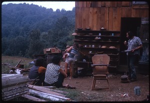 COmmune members, with infant, seated outside the house at Johnson Pasture Commune
