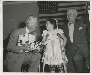 Bruce Barton handing diploma to young girl wearing braces and crutches