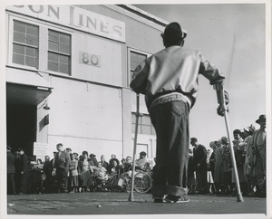 Man on crutches walks towards crowd