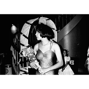 Teenage girl in a party dress holding a bouquet of flowers.