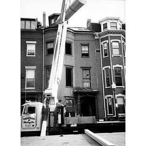 Lumber being hoisted by a crane to the top story of 326 Shawmut Avenue.