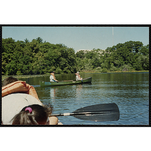 Children paddle canoes on a lake