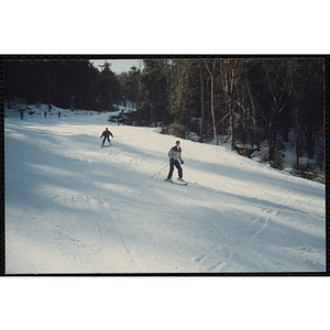 Two boys ski down a slope