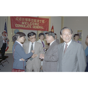 Men chat with a woman at a welcome party for the Consulate General of the People's Republic of China