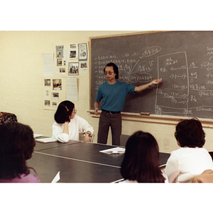 Man stands at a chalkboard while teaching at a job training class