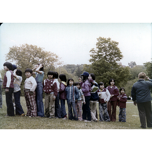 Children stand in a line in a grassy field