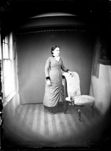 Full length portrait of a woman standing next to a chair