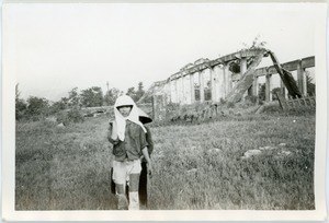 Woman shielding another from photographer, with ruins behind them