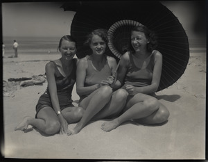 Isabelle Moulton, Mrs. Stewart Sanborn (Miriam?), and Mrs. Riker in bathing suits at the beach, seated under a parasol