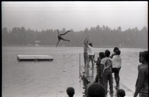 Group of summer campers (?) tossing a child into a lake, one onlooker wearing a Spirit in Flesh t-shirt