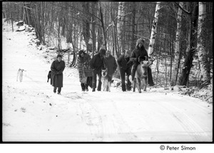 Group walking up snowy hill, one man riding on a pony