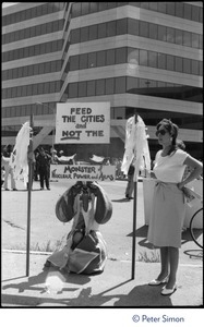 Protester associated with Mobilization for Survival at an antinuclear demonstration near Draper Laboratory, MIT, carrying a sign reading 'Feed the cities and not the monster of nuclear power and arms'
