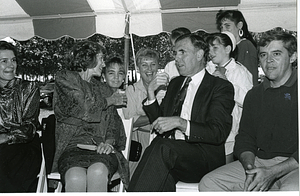 Mayor Raymond L. Flynn and wife Catherine (Kathy) sitting under tent with unidentified group of people
